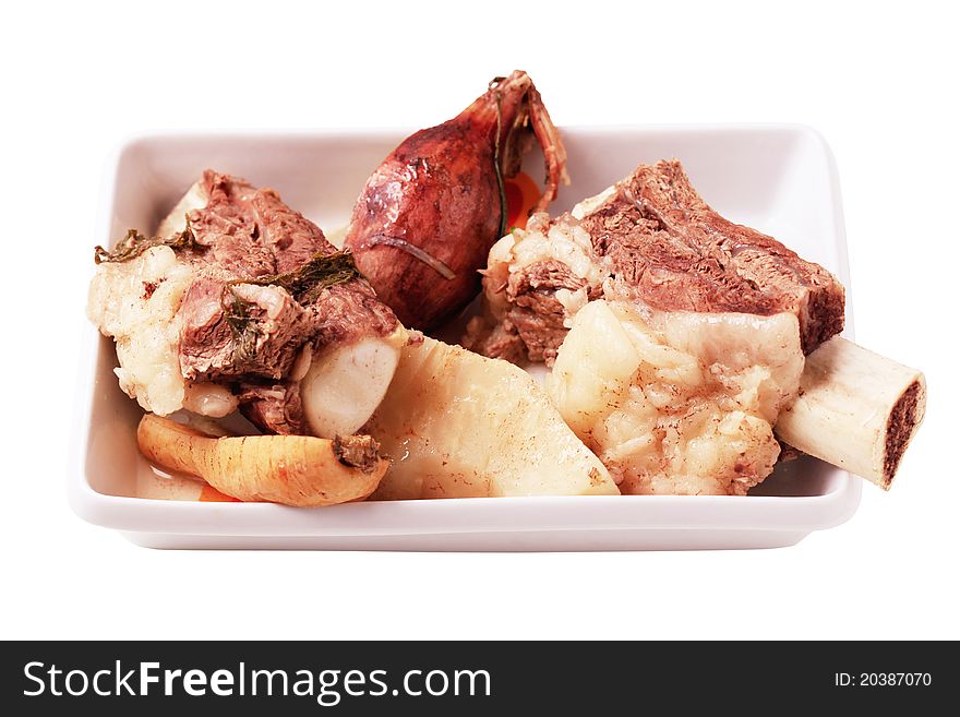 Boiled beef and root vegetables in a porcelain dish - cut out on white