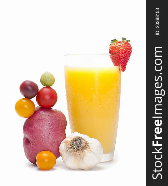A glass of orange juice, decorated with a strawberry. Arrangement of potato, tomatoes and a garlic at the side. A glass of orange juice, decorated with a strawberry. Arrangement of potato, tomatoes and a garlic at the side.