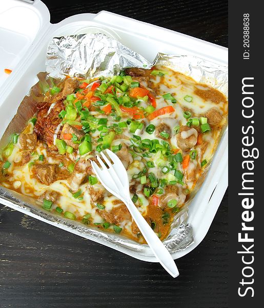 Tasty, colorful take out food in a box. Potato pancake with meat and vegetables covered in chease and sauce. Tasty, colorful take out food in a box. Potato pancake with meat and vegetables covered in chease and sauce.