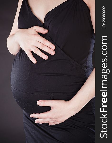 Young fresh pregnant woman with blow bubbles sitting on a couch over black background.