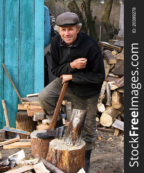 A man stands next to the deck leaning on an axe. A man stands next to the deck leaning on an axe