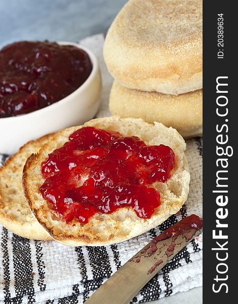 English muffins, one cut and spread with strawberry jam.