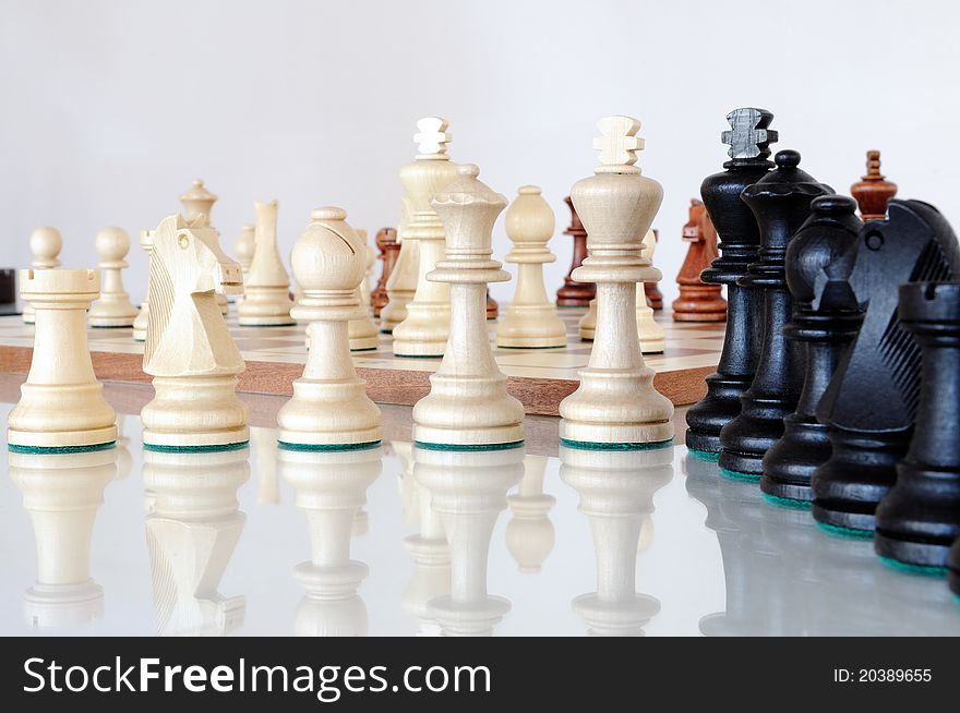 Chess pieces on wood board, black and white, reflection