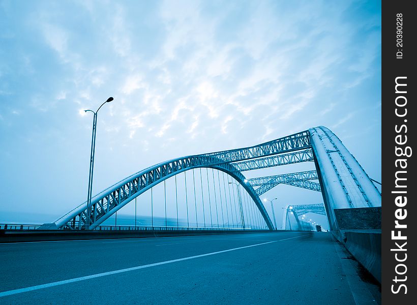 Road through the bridge with blue sky background of a city.