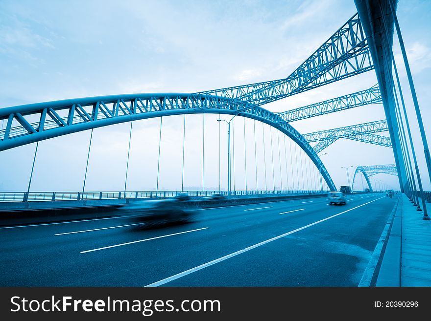 Road through the bridge with blue sky background of a city.