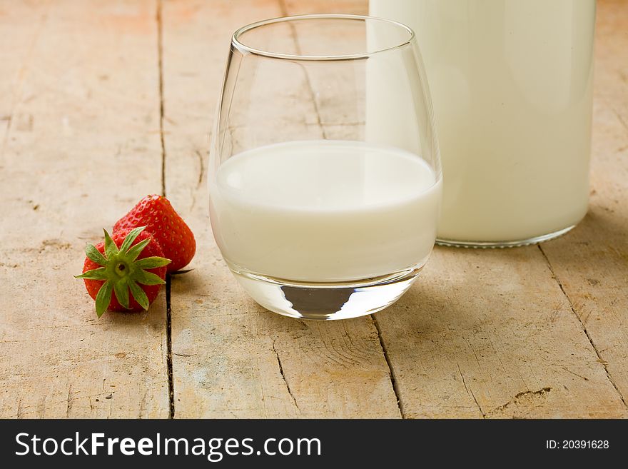 Photo of cup of milk with strawberry on wooden table. Photo of cup of milk with strawberry on wooden table