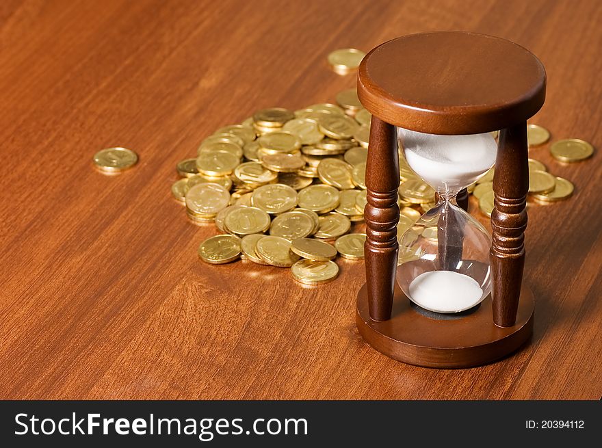 Hourglasses And Coin On Wooden Table