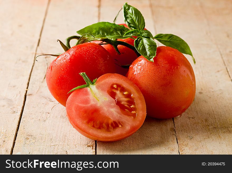 Photo of delicious fresh tomatoes with basil leaves on wooden table