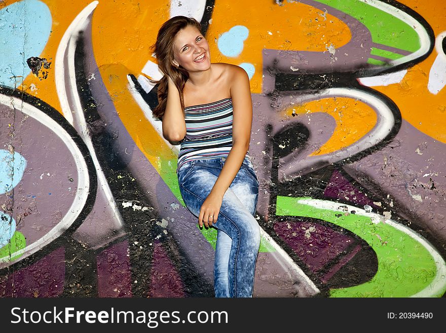 Beautiful girl near graffiti wall background.