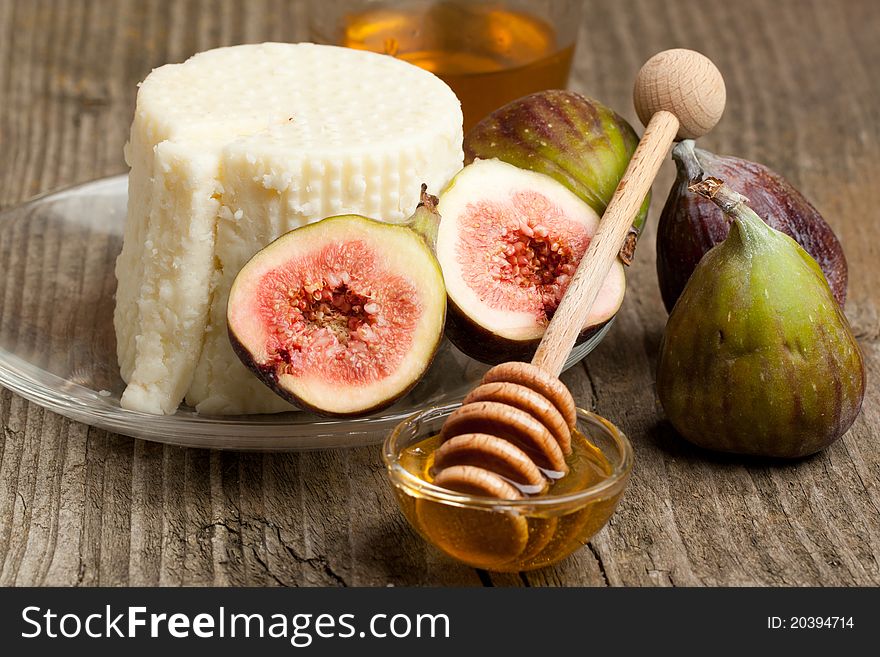 Plate with white cheese and fresh figs with honey on old wooden table. Plate with white cheese and fresh figs with honey on old wooden table