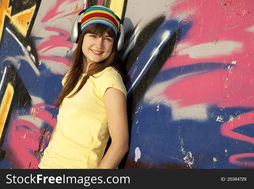 Girl with headphones and graffiti wall