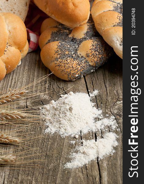 Lot of bread with spikes of rye and flour on old wooden table