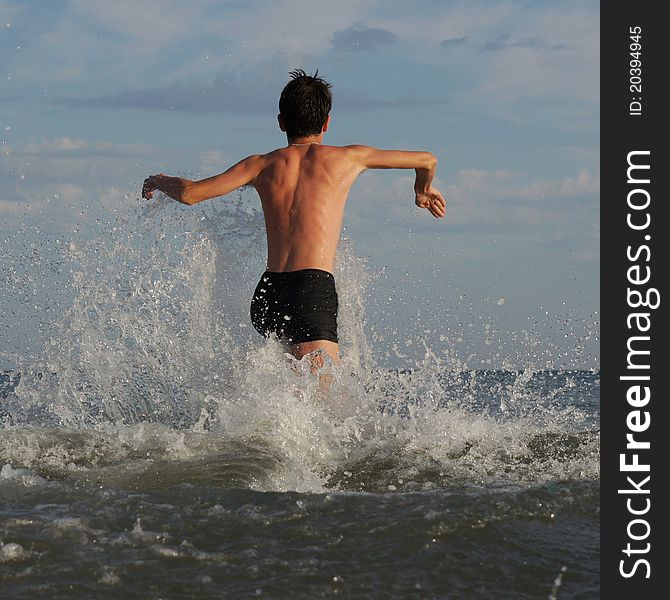 Boy running along the beach before swimming