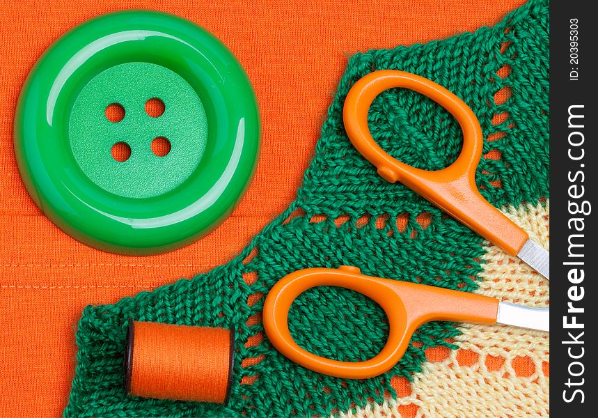 Scissors, button, threads on fabric background