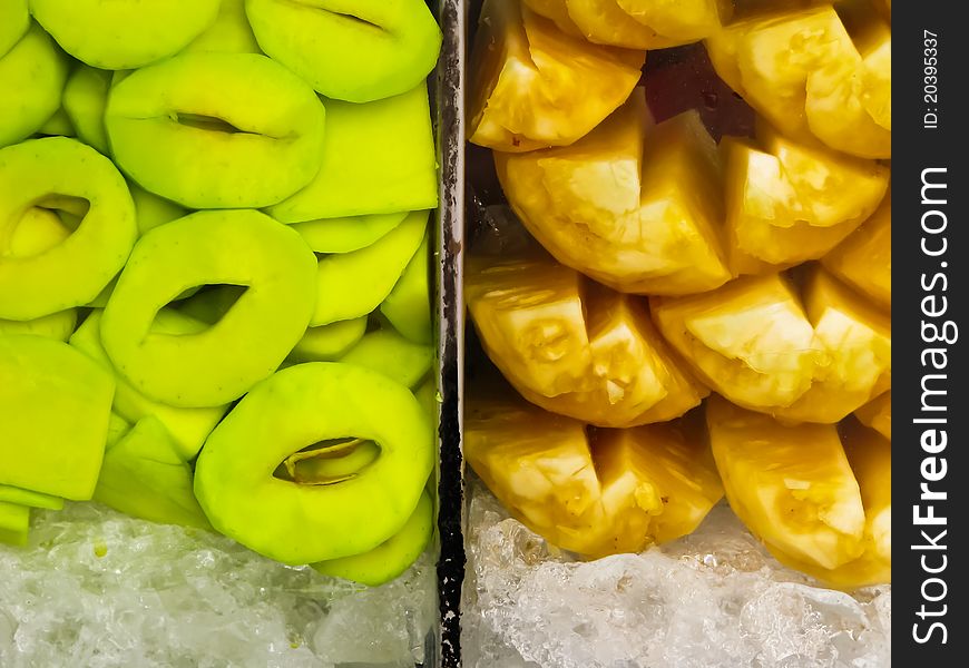 Fresh green mango and pineapple in glass case with ice. Fresh green mango and pineapple in glass case with ice