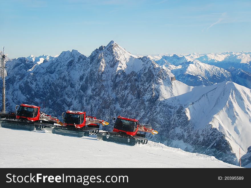 Piste preperation vehicles with view over the alps. Piste preperation vehicles with view over the alps