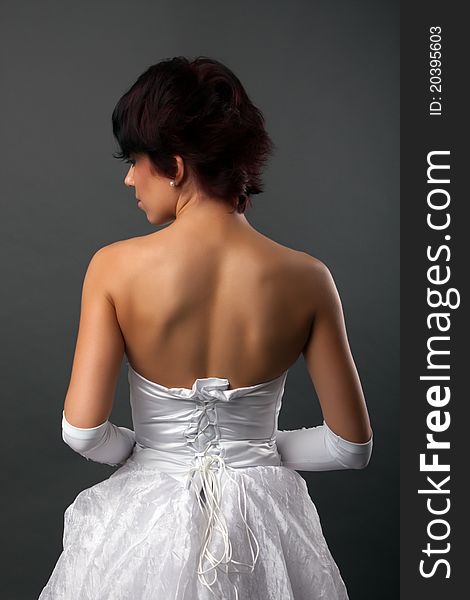 Back view of beautiful brunette bride over gray studio background. Back view of beautiful brunette bride over gray studio background