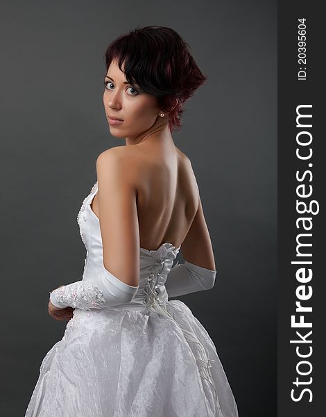 Back view of beautiful brunette bride over gray studio background. Back view of beautiful brunette bride over gray studio background