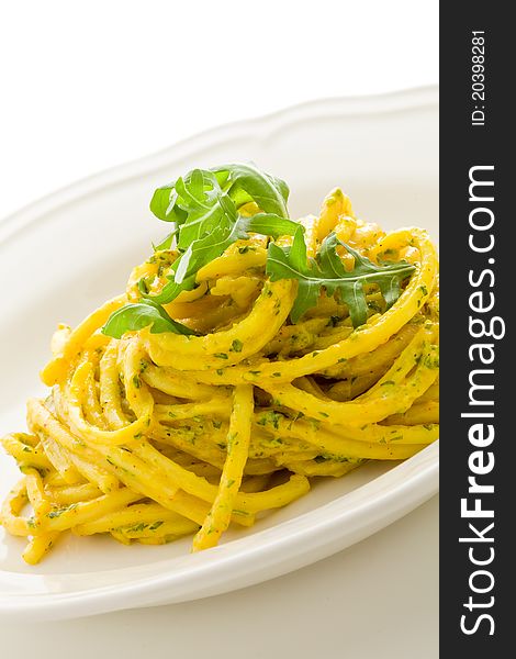 Photo of delicious pasta with saffron and arugula pesto on isolated background. Photo of delicious pasta with saffron and arugula pesto on isolated background