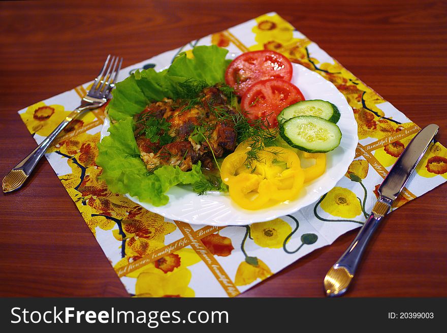 The meat baked with cheese lies on a plate with vegetables. Shallow DOF