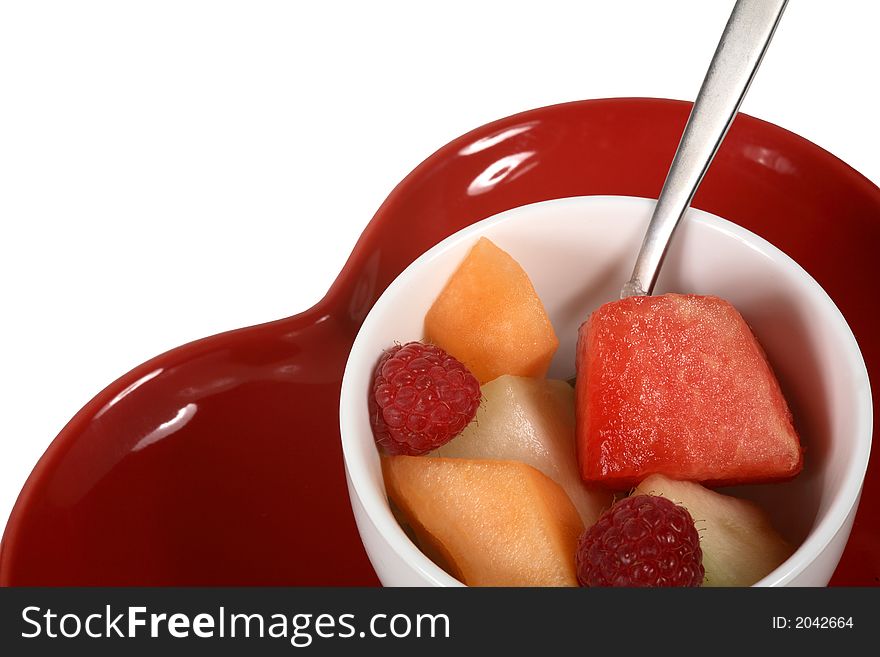 Healthy bowl of fresh fruit on a red heart shaped dish. Healthy bowl of fresh fruit on a red heart shaped dish