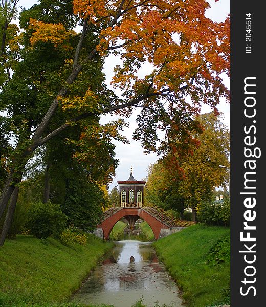 The beautiful bridge through small river, trees, autumn