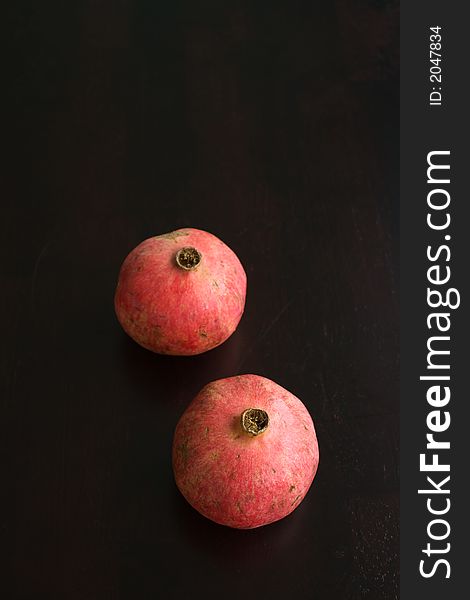 Whole Pomegrantes on a dark wooden table