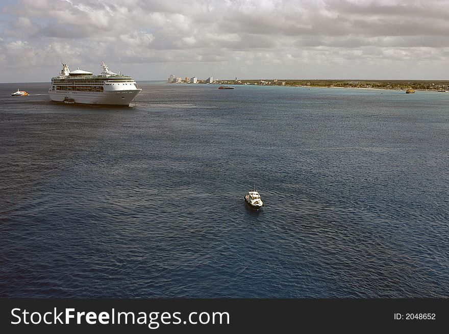 A view of the Isle of Cozumel with several boats and a ship anchored.