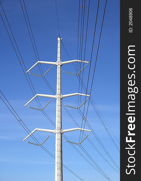 White high voltage electricity pylon and power lines against the blue sky. White high voltage electricity pylon and power lines against the blue sky.