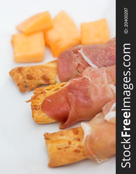Prosciutto on grissini and melon on the plate