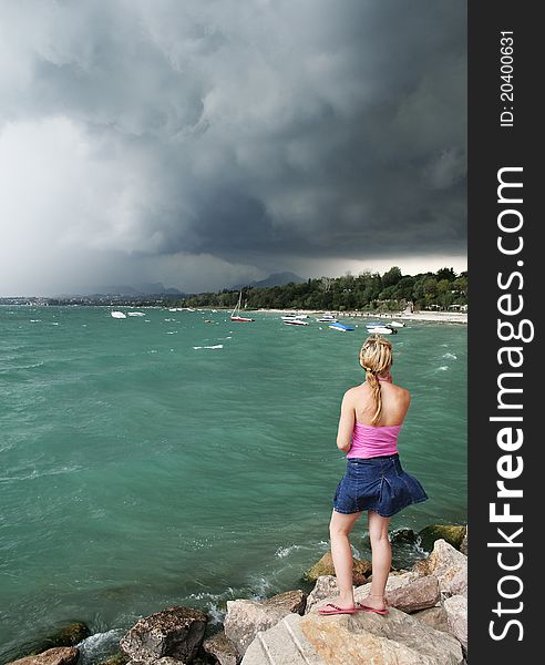 Young woman staying on the rocks and watching the storm. Young woman staying on the rocks and watching the storm