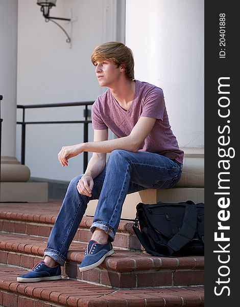 Vertical photograph of a young male college student on the steps of a campus building. Vertical photograph of a young male college student on the steps of a campus building