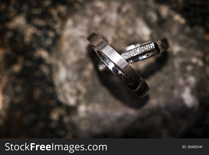 Wedding rings on a rocky background, with vignette effect