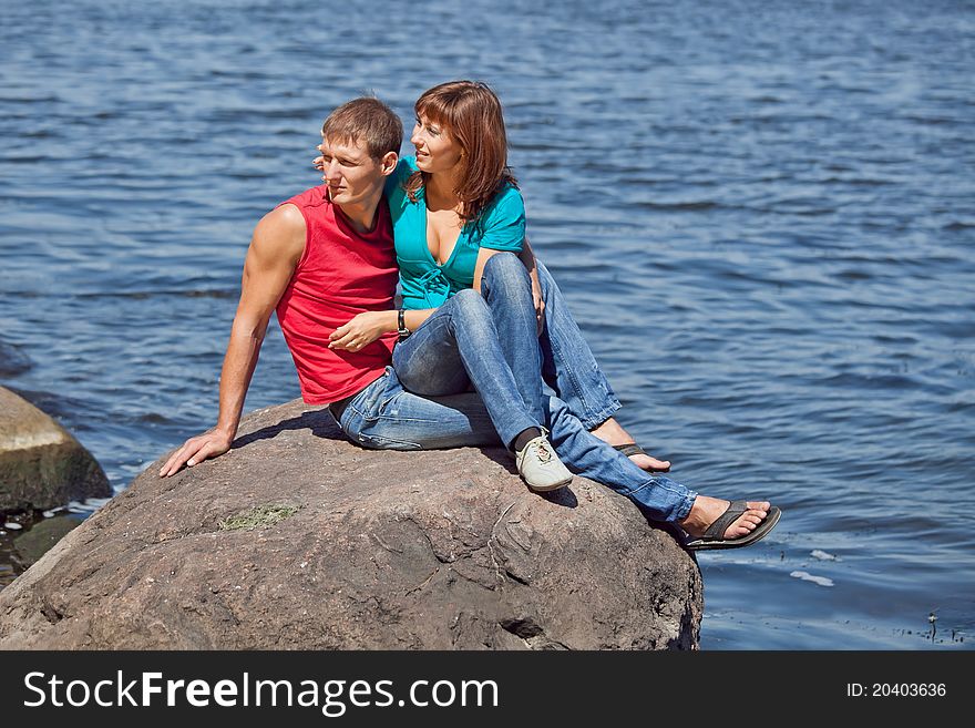 The loving couple sits on a stone on an coast. The loving couple sits on a stone on an coast