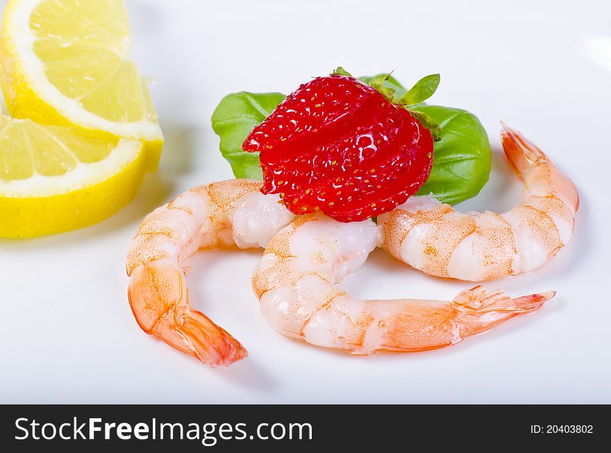 Shrimp with strawberries and lemon on the plate