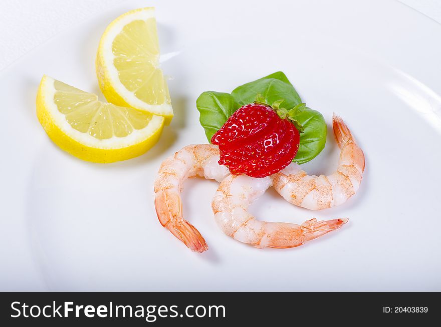 Shrimp with strawberries and lemon on the plate
