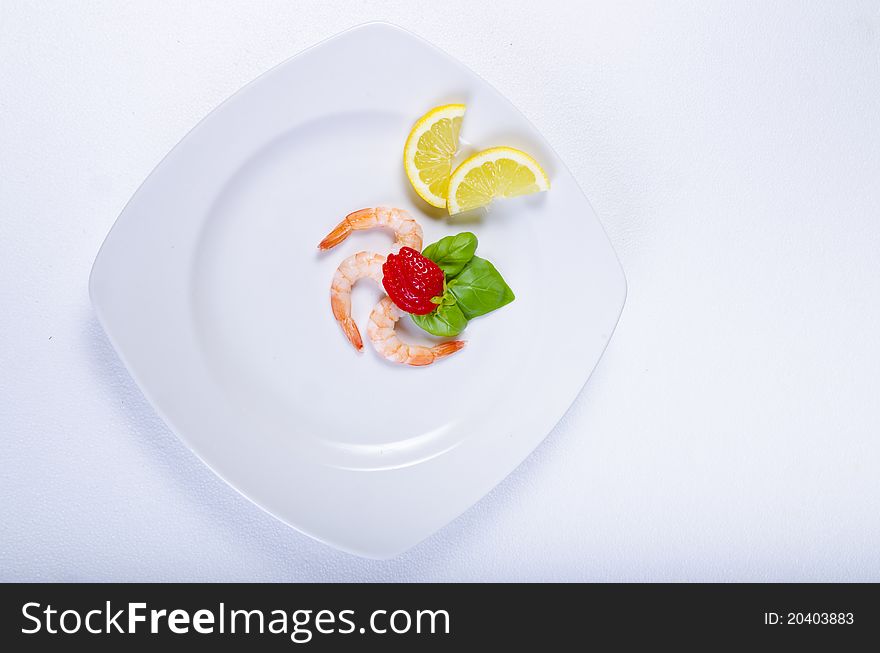 Shrimp with strawberries and lemon on the plate