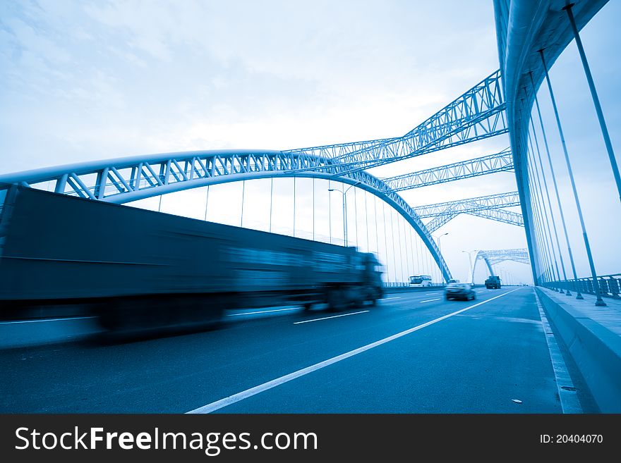 Road through the bridge with blue sky background of a city.