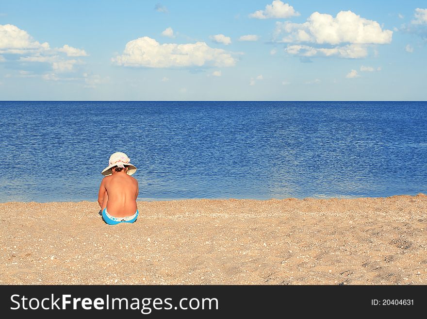 A girl sitting on a summer evening on the beach. A girl sitting on a summer evening on the beach