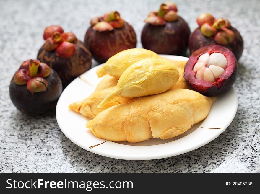 Close up of peeled durian and mangosteens over granite surface.