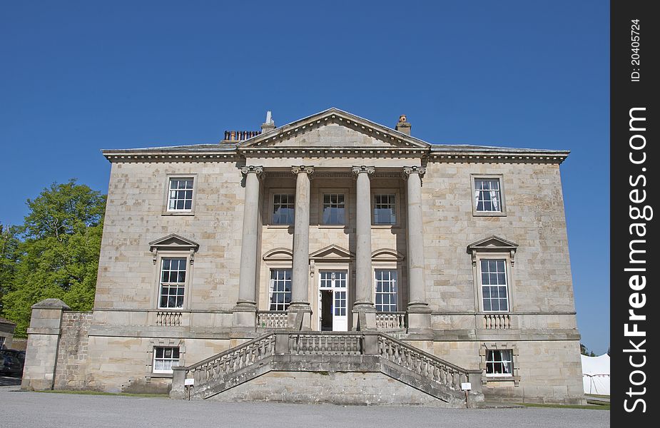 An Eighteenth CenturyStately Home built in the Palladian Style with Ionic pillars under a blue sky. An Eighteenth CenturyStately Home built in the Palladian Style with Ionic pillars under a blue sky