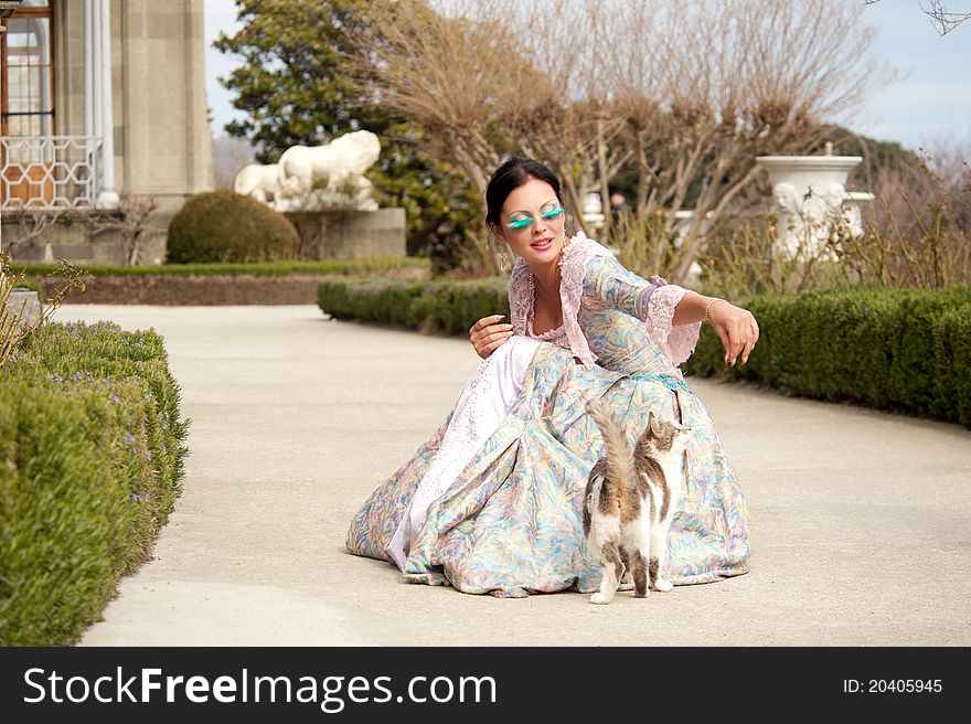 Woman in classical dress goes through the alley next to the cat. Woman in classical dress goes through the alley next to the cat