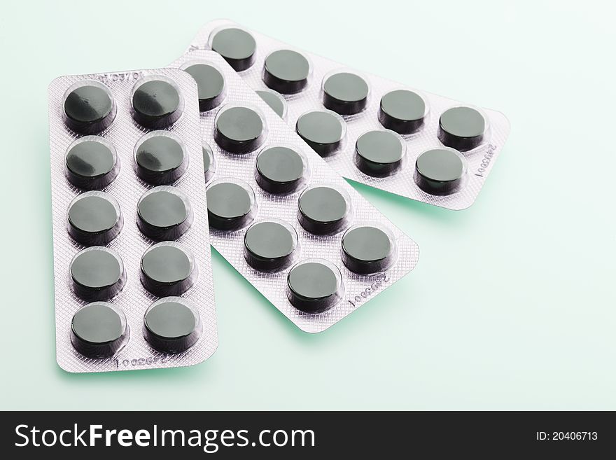 Charcoal tablets in packing material on green background