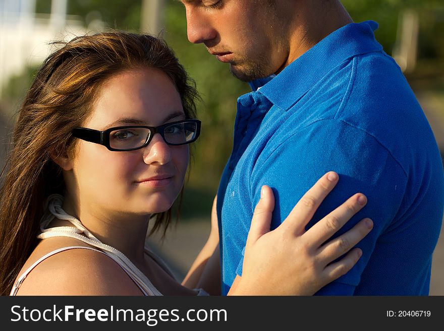 A young woman embraces a young man and is looking at the camera