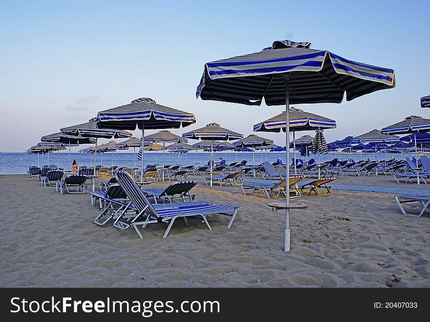 Beach, sunbeds and white and blue parasols. Beach, sunbeds and white and blue parasols