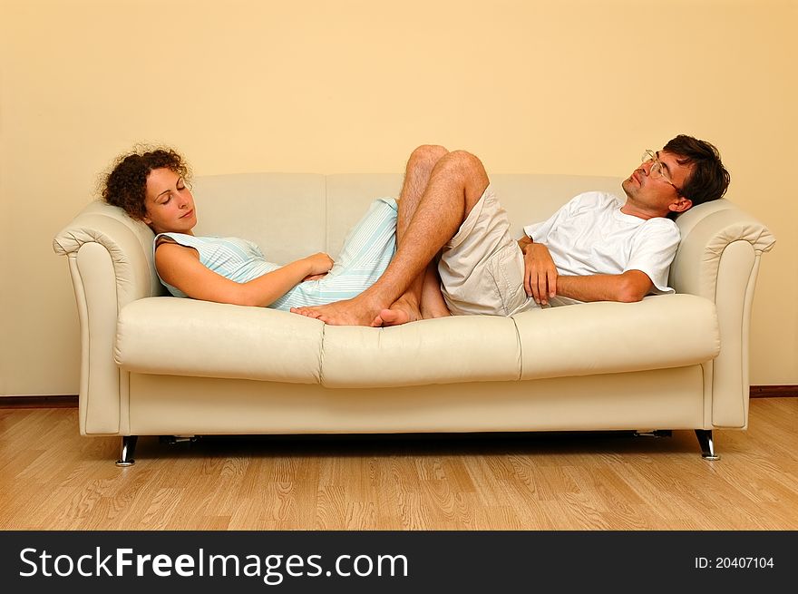 Young woman and man repose on the white sofa