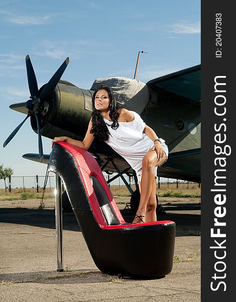 Woman in a white dress and chair stands near the plane. Woman in a white dress and chair stands near the plane