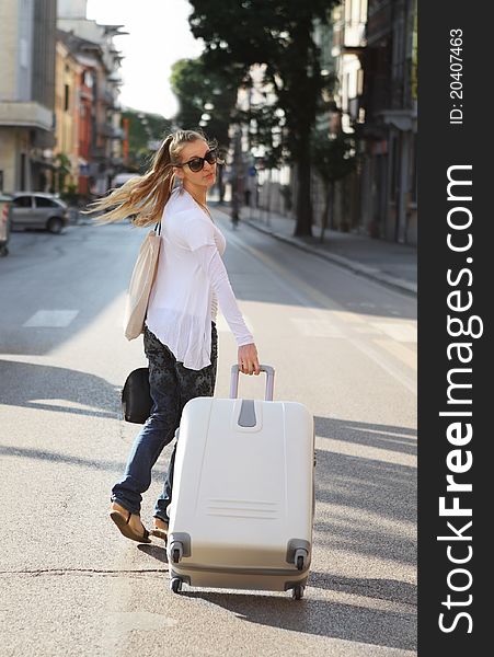 Beautiful young woman with a white suitcase