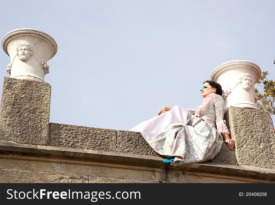 Woman in a magnificent dress sitting on a stone slab