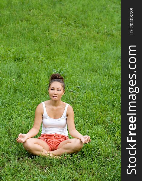 Girl meditating on meadow in park